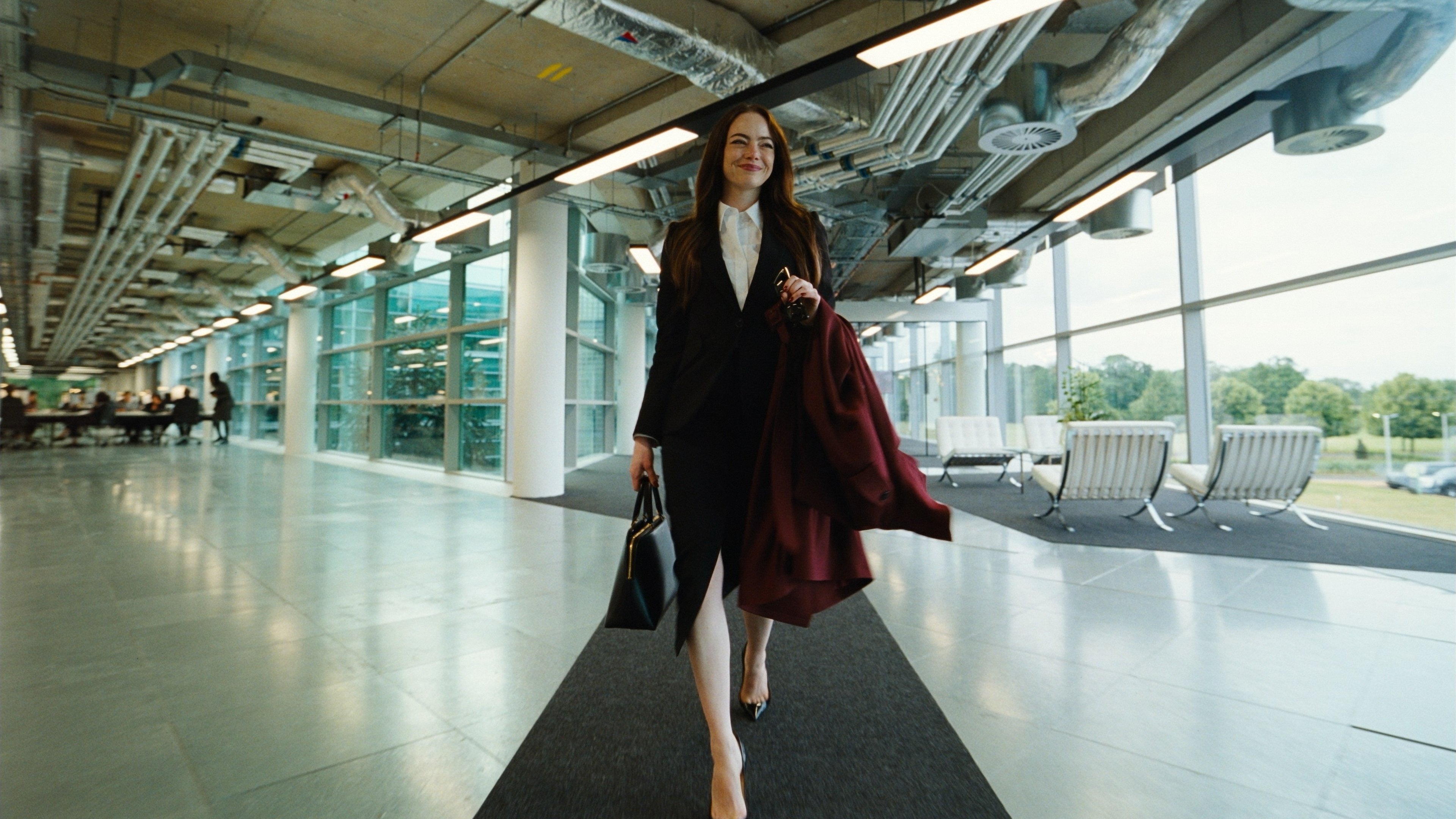 Caption: a woman walking down a walkway carrying a purse