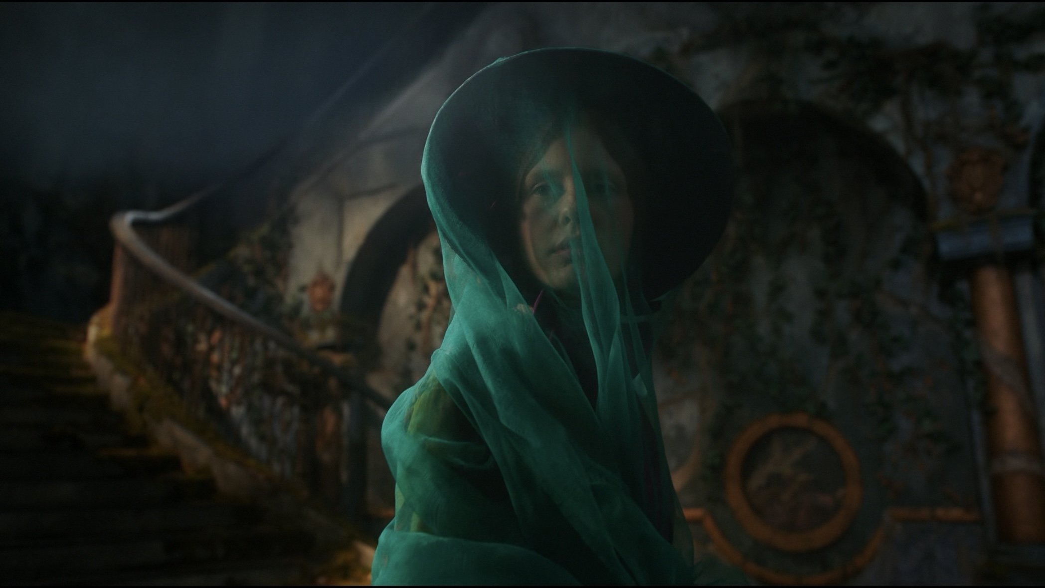 Caption: a woman in a green dress and a black hat