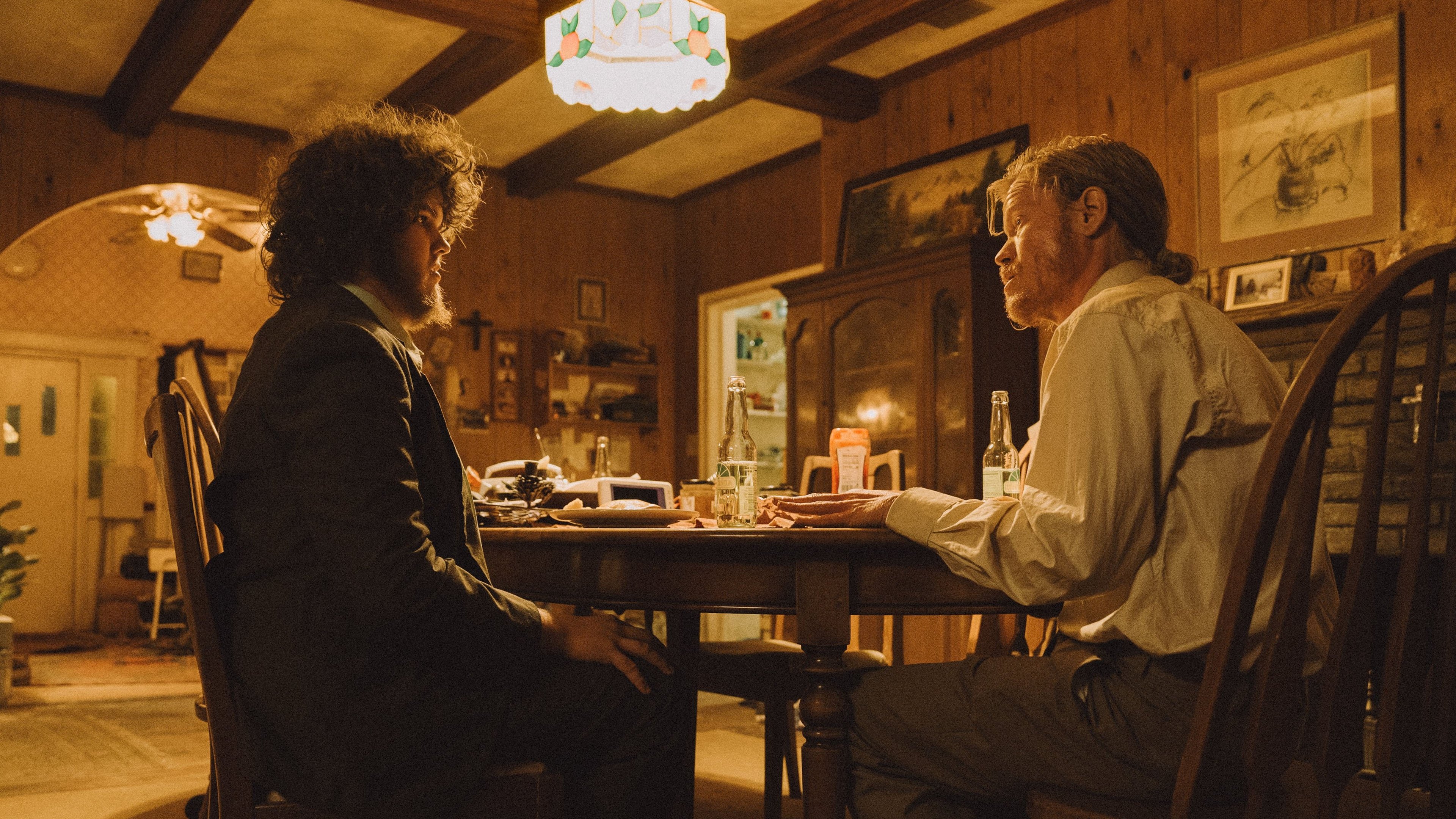 Caption: two men sitting at a table talking to each other