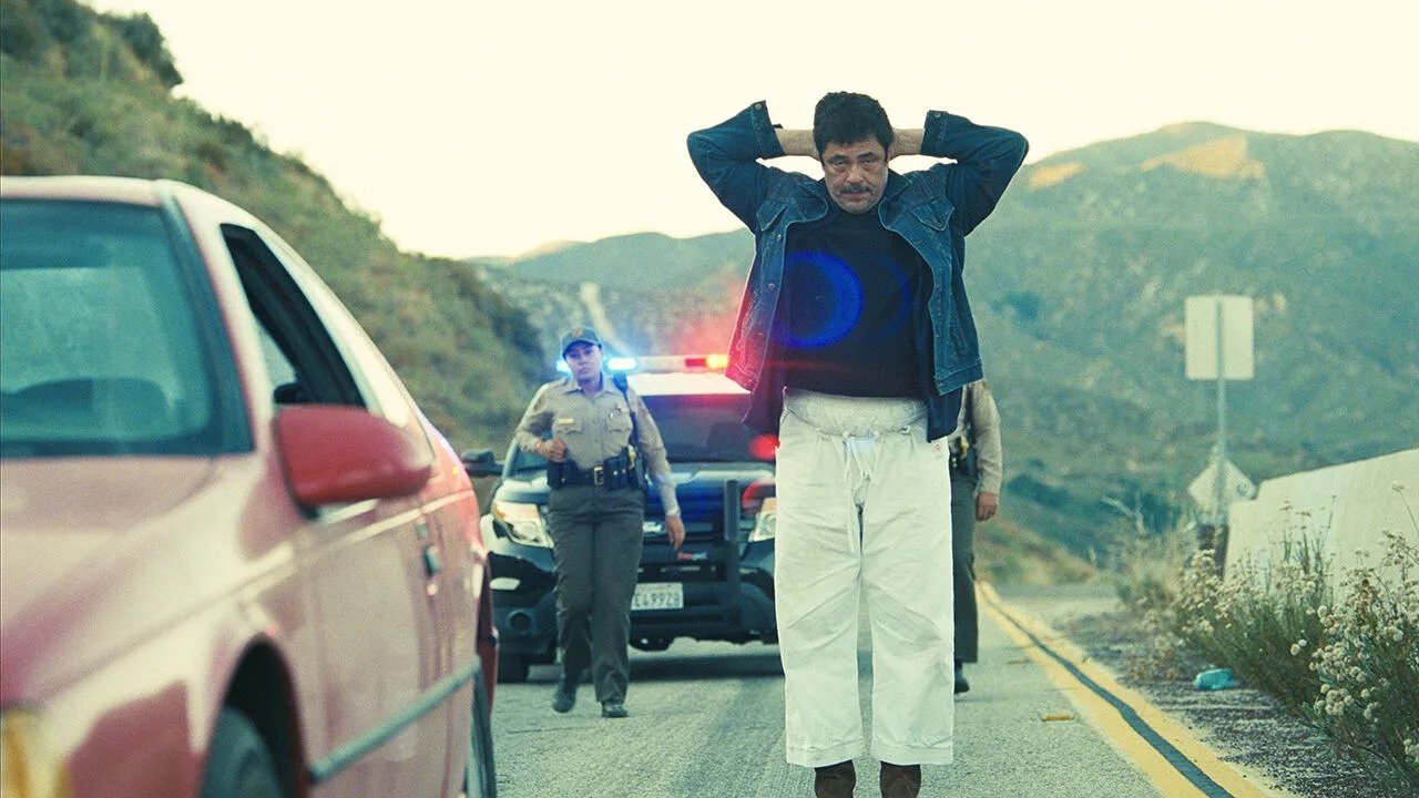 Caption: a man standing on the side of a road next to a police car