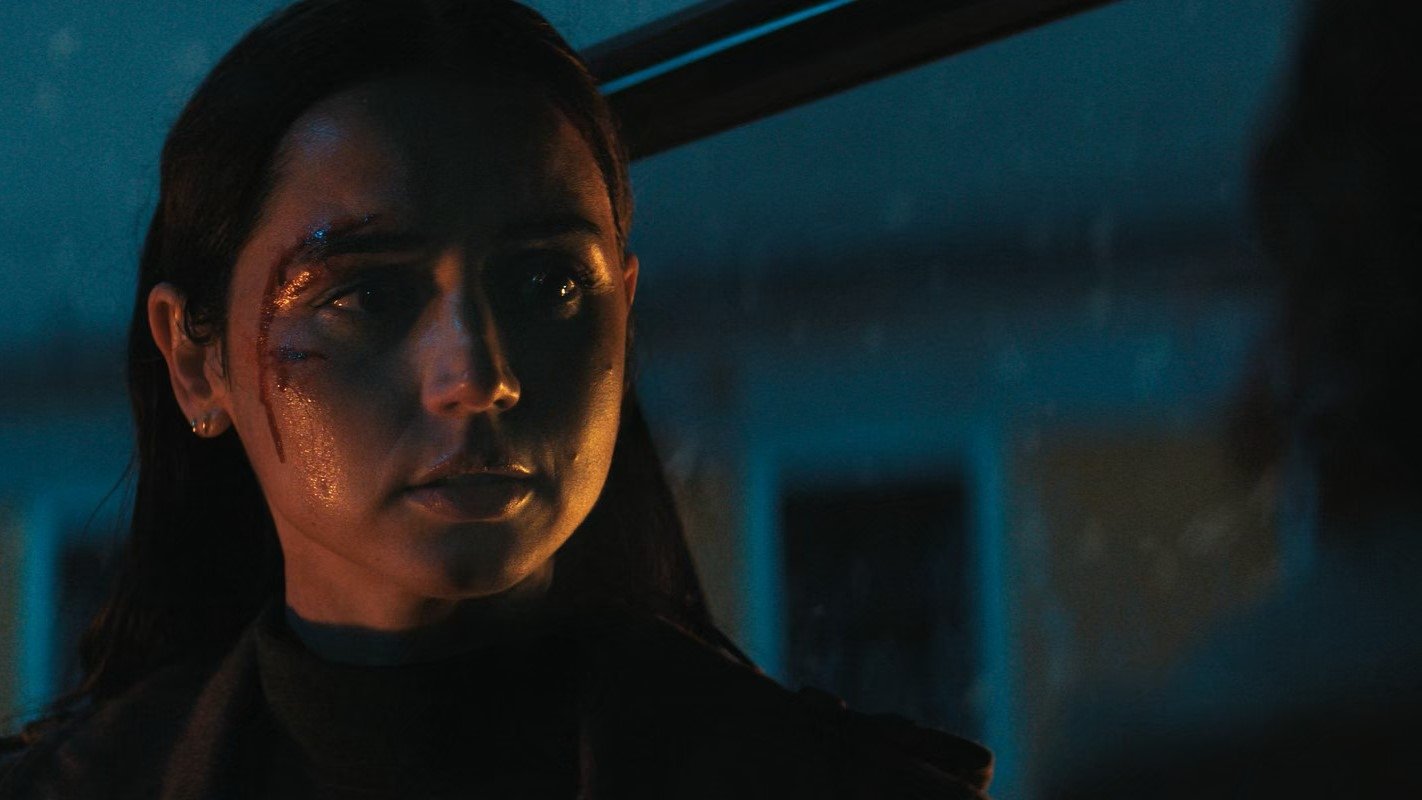 Caption: a woman in a dark room staring at the camera