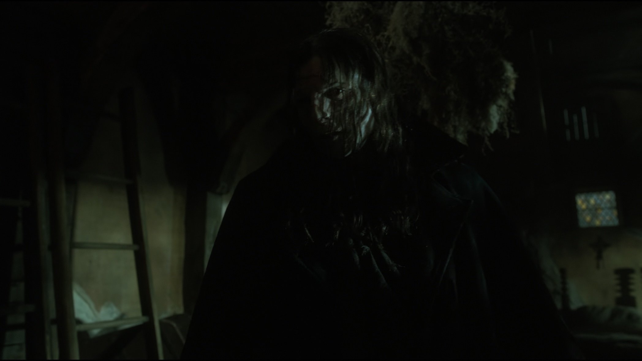 Caption: a man with long hair standing in a dark room