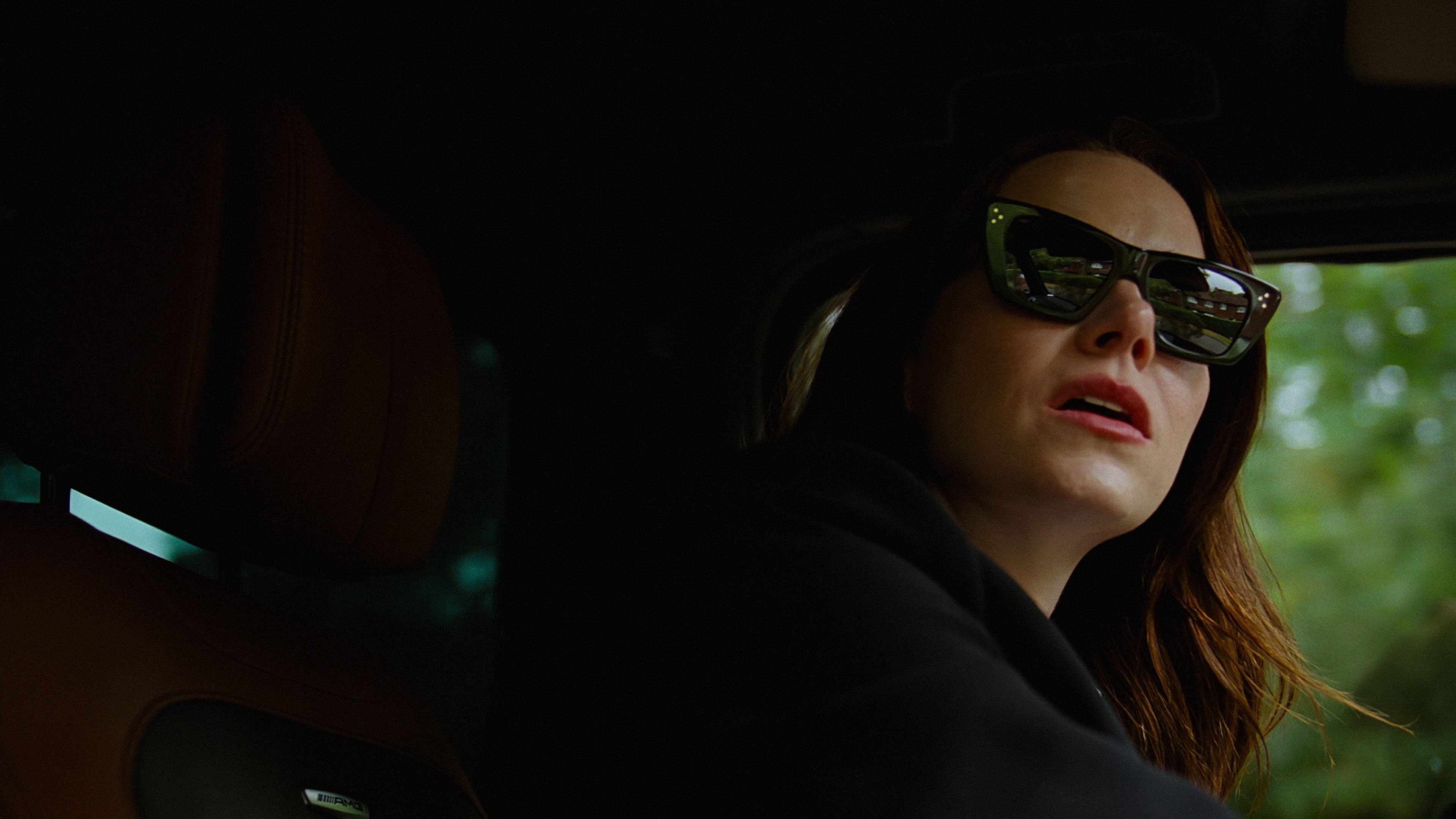 Caption: a woman wearing sunglasses sitting in a car