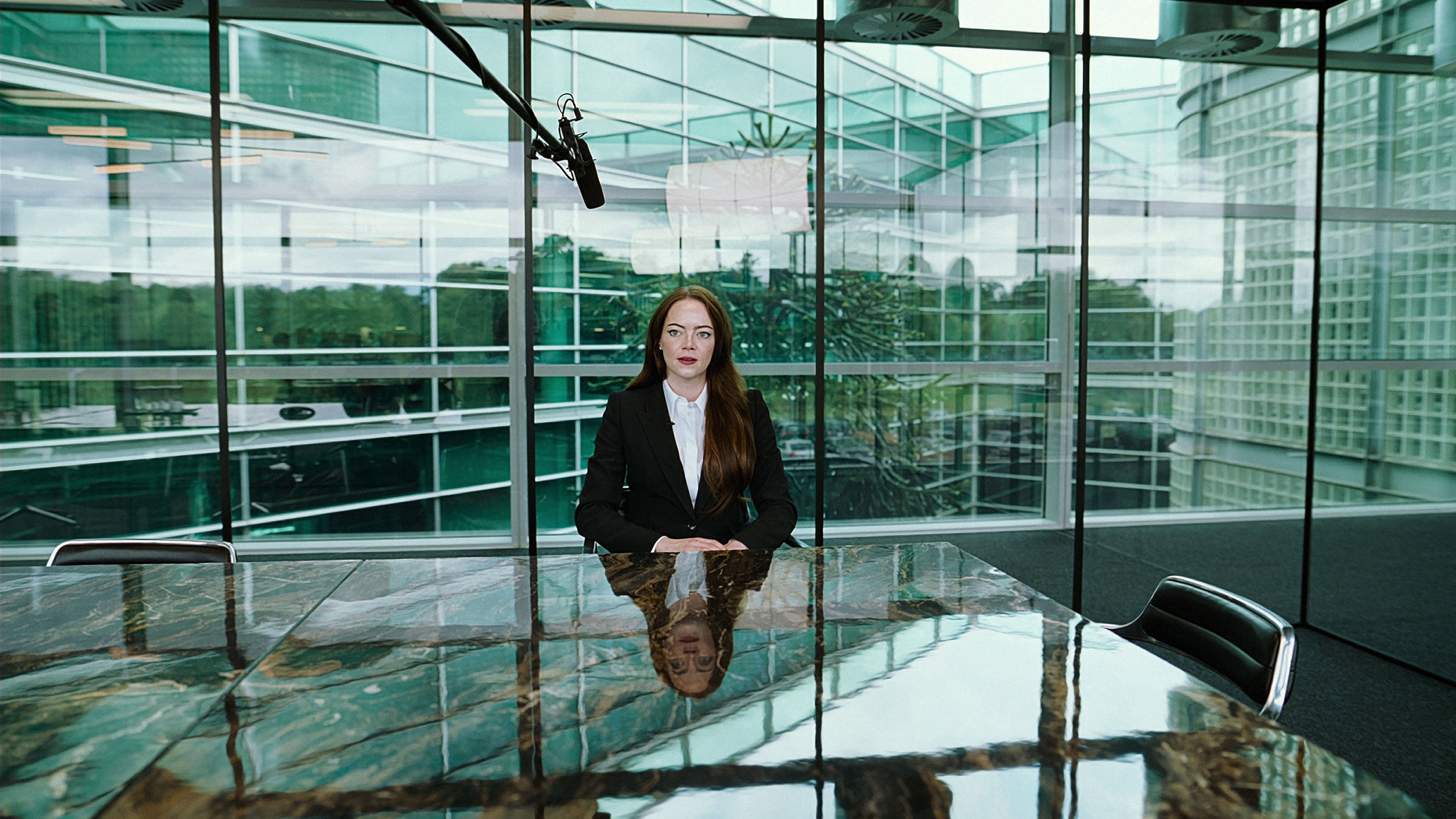 Caption: a woman sitting at a table in front of a glass wall