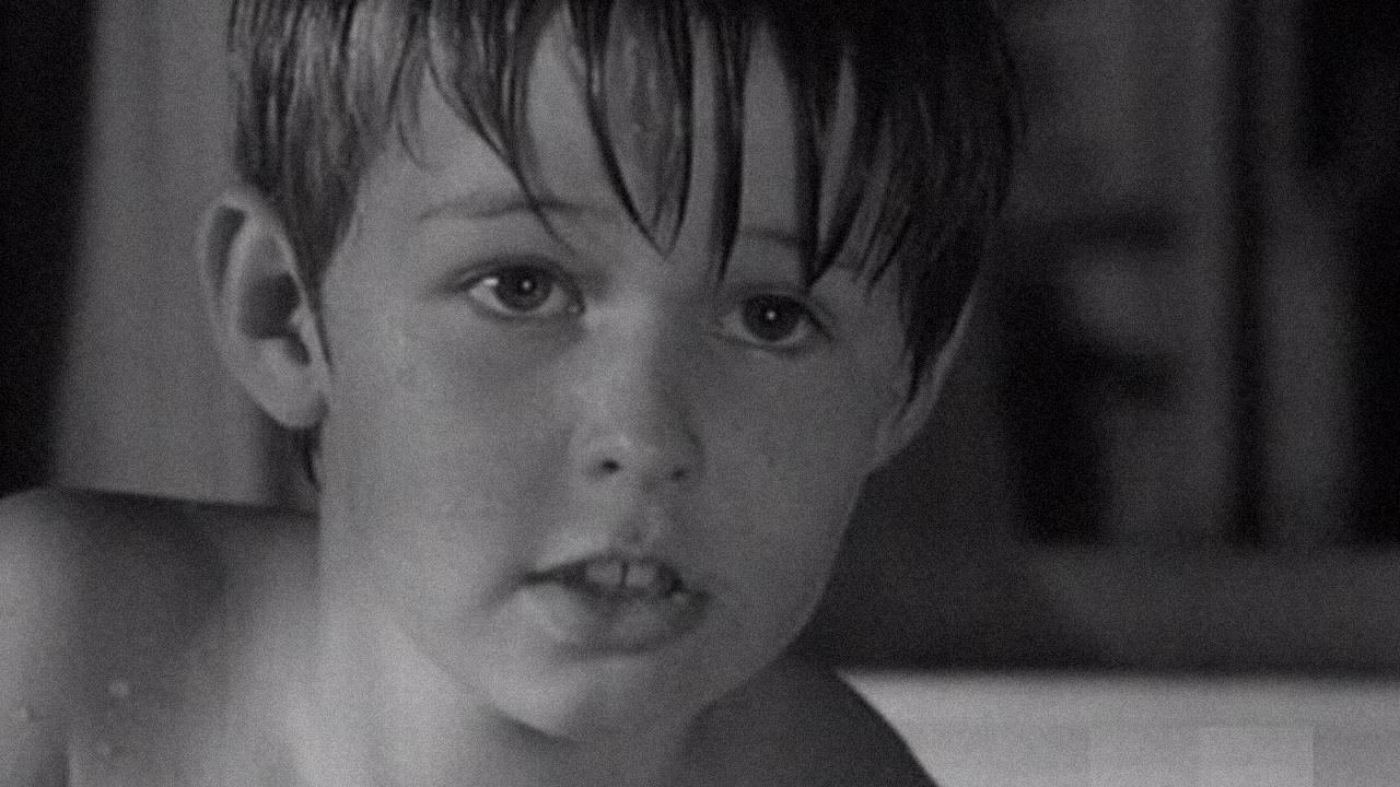 A young boy about 10 or 11 is playing in the woods by himself. 