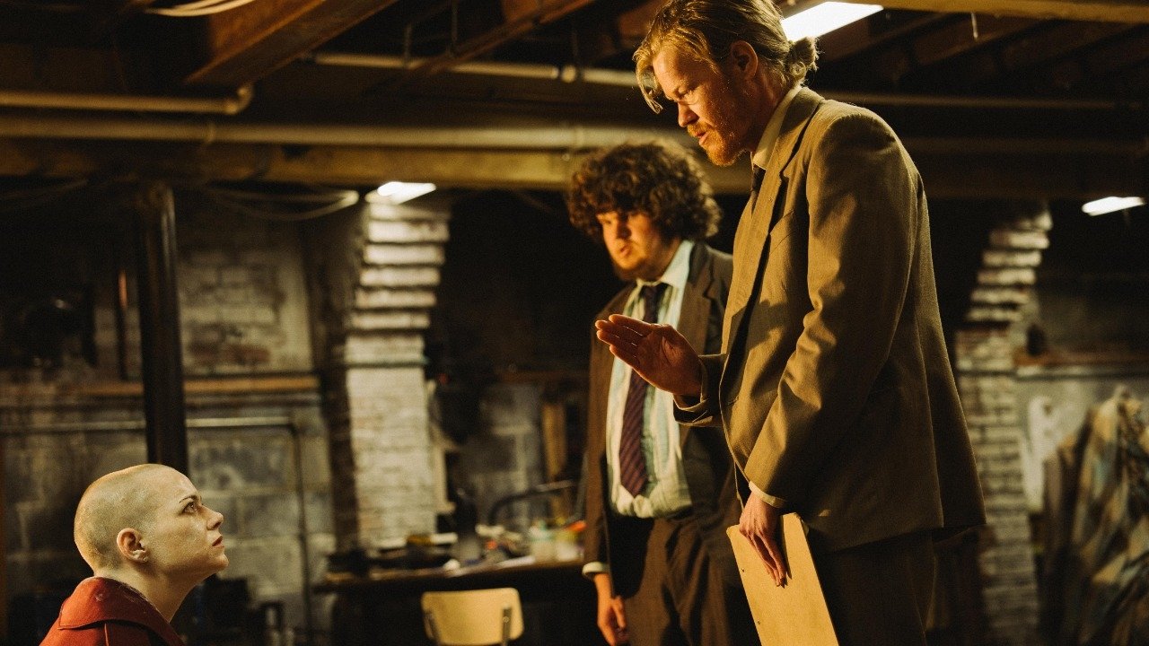 Caption: a man standing next to another man in a room