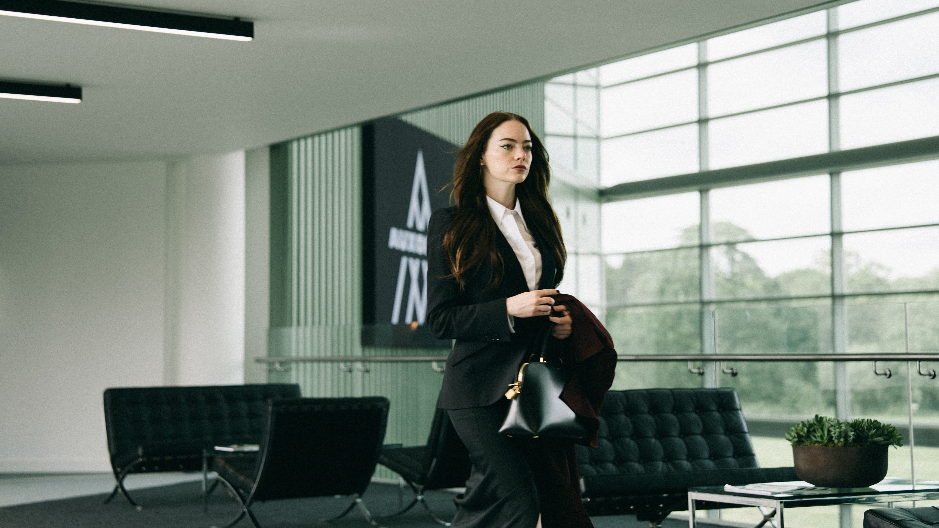 Caption: a woman in a suit walking through a lobby
