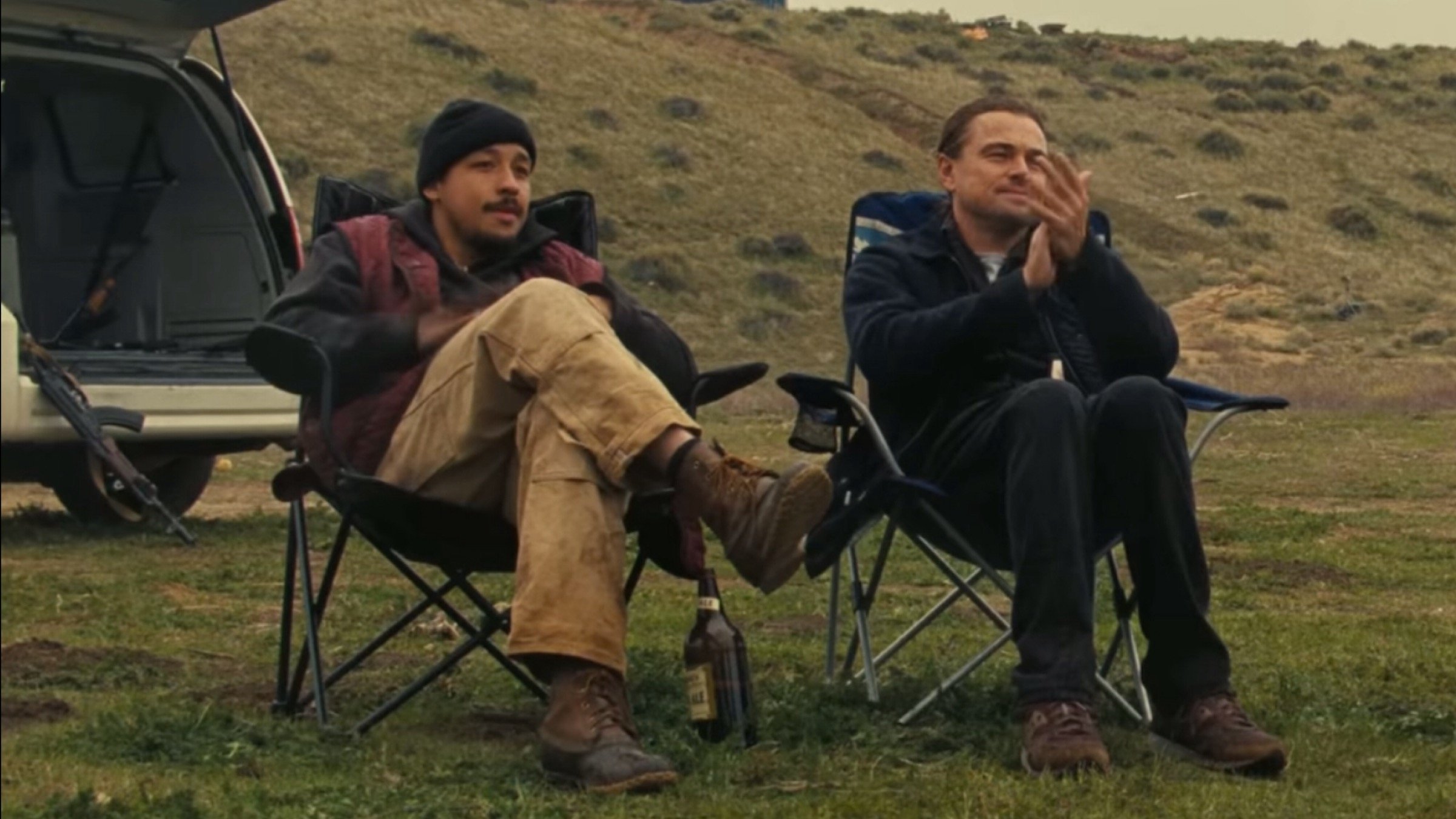 Caption: two men sitting in folding chairs in front of a van