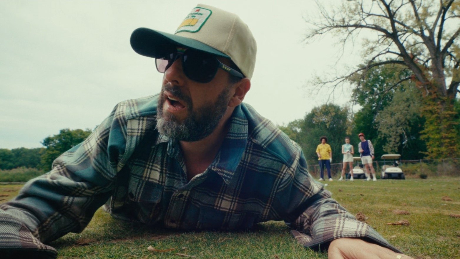 Caption: a man laying on the ground wearing a hat and sunglasses