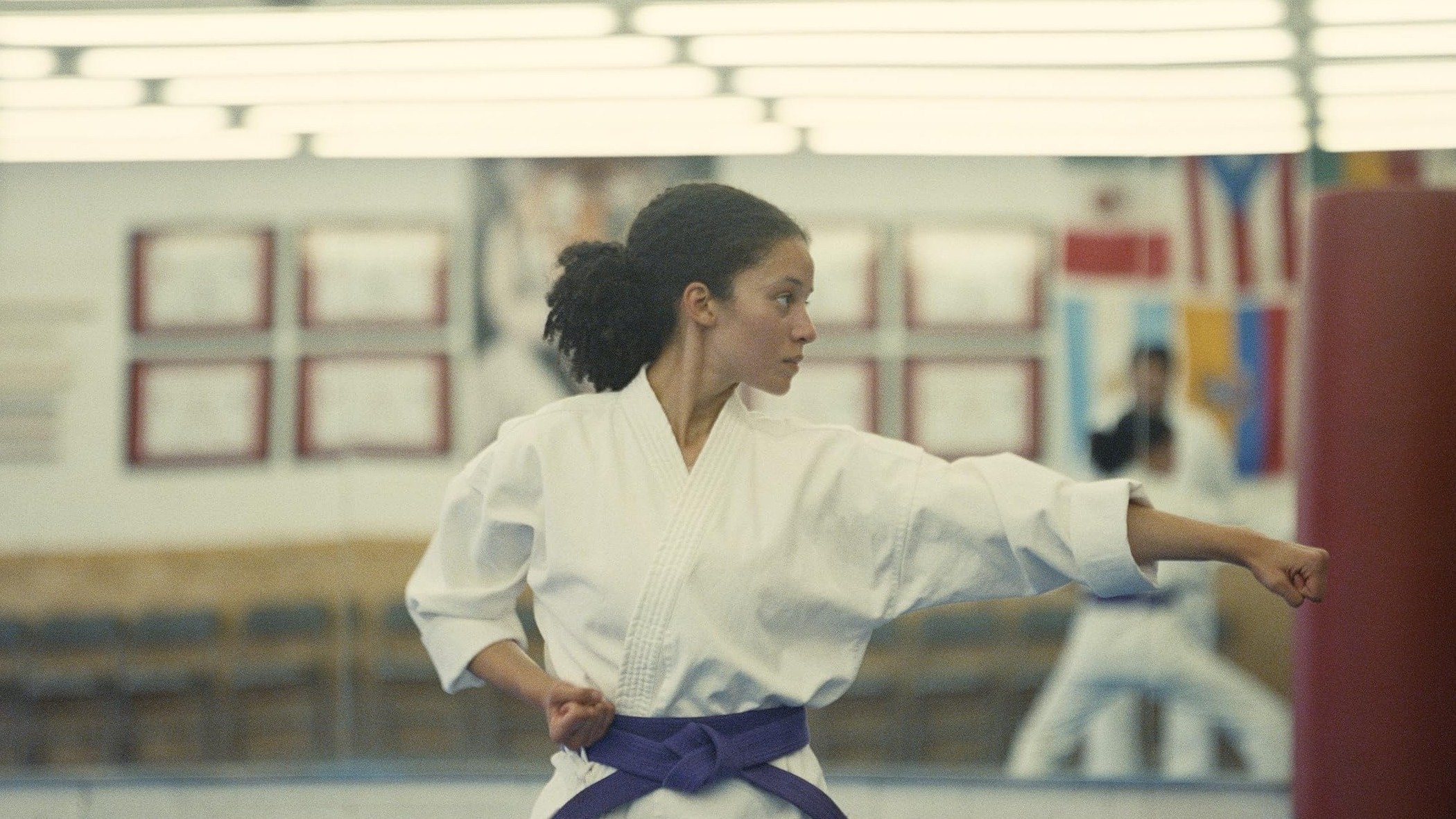 Caption: a woman in a white kimono is practicing karate