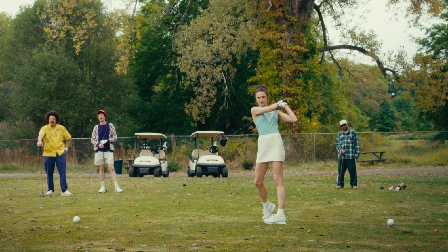 Caption: a group of people playing a game of golf