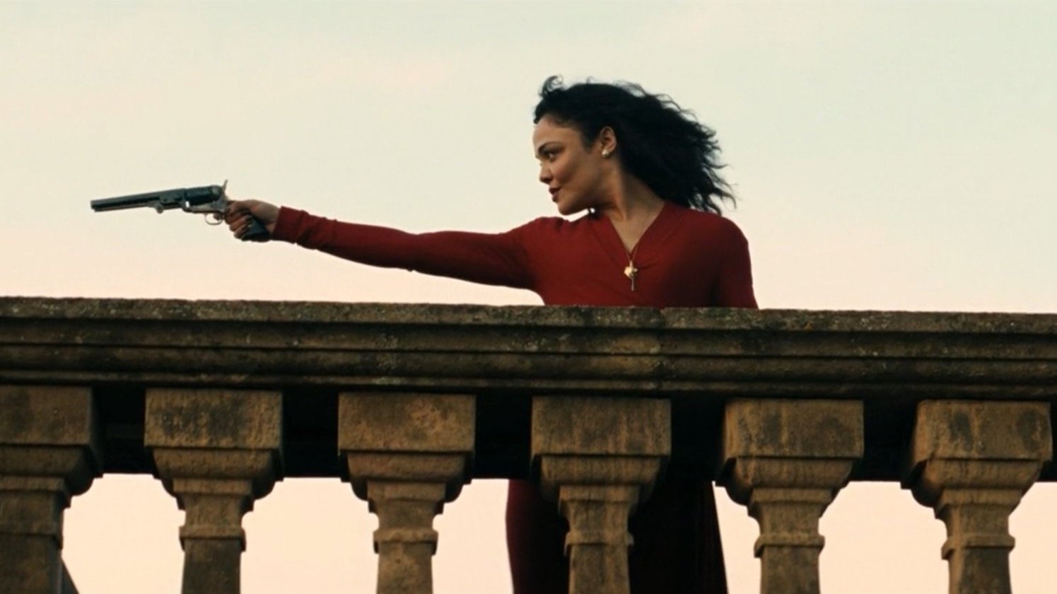 Caption: a woman holding a gun on top of a balcony