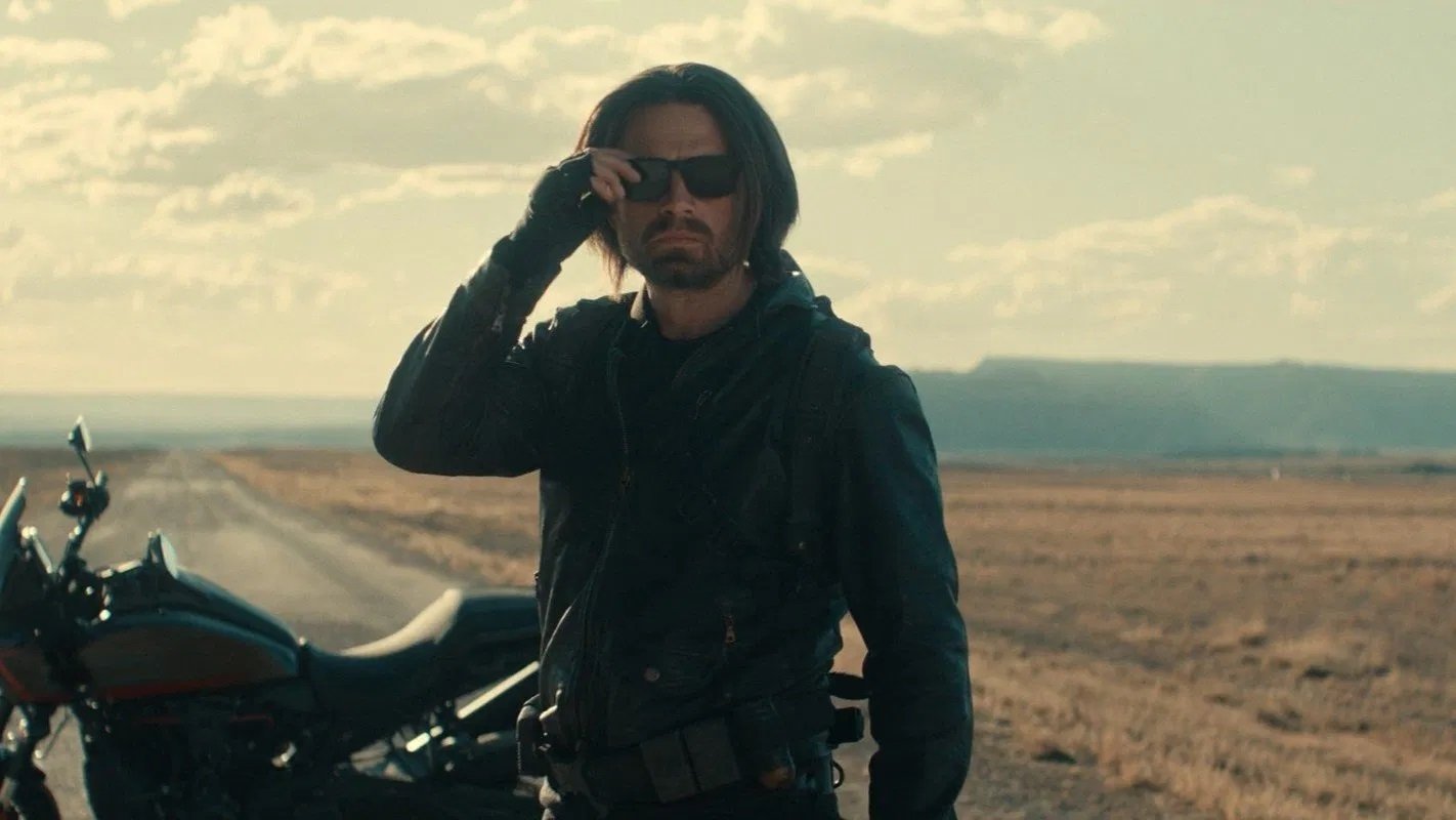 Caption: a man standing next to a motorcycle on a road