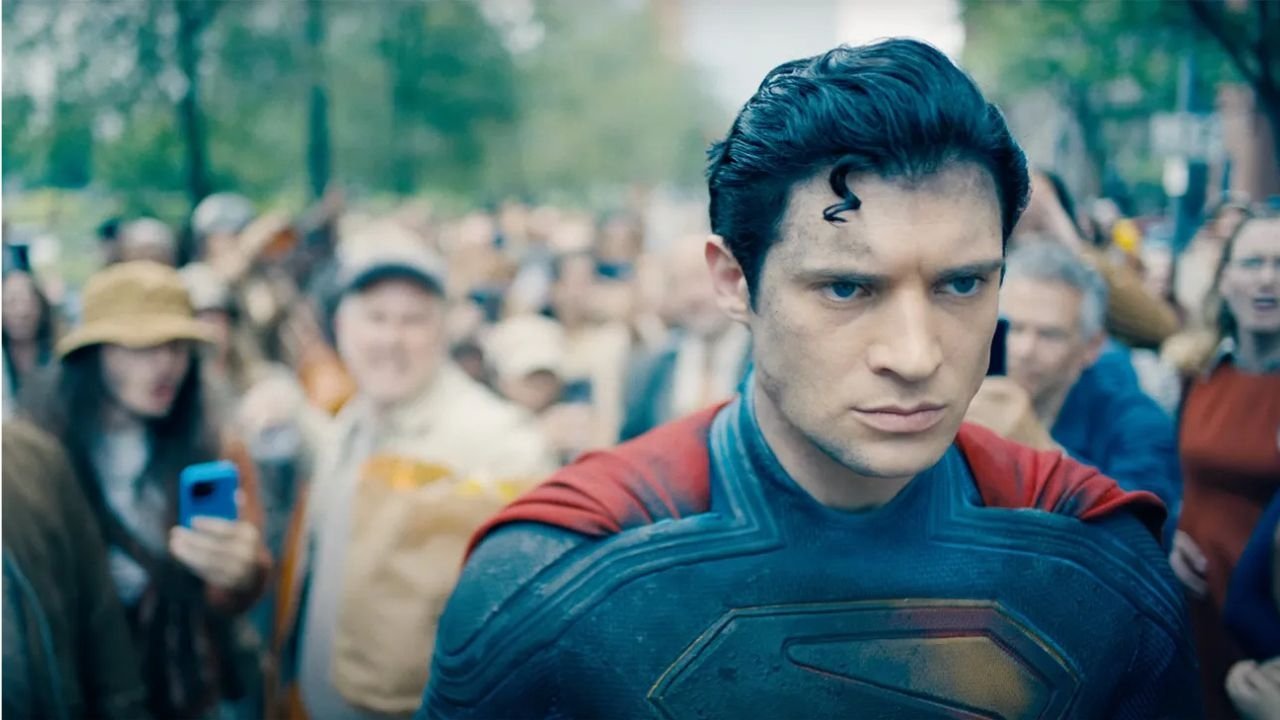 Caption: a man in a superman costume standing in front of a crowd of people