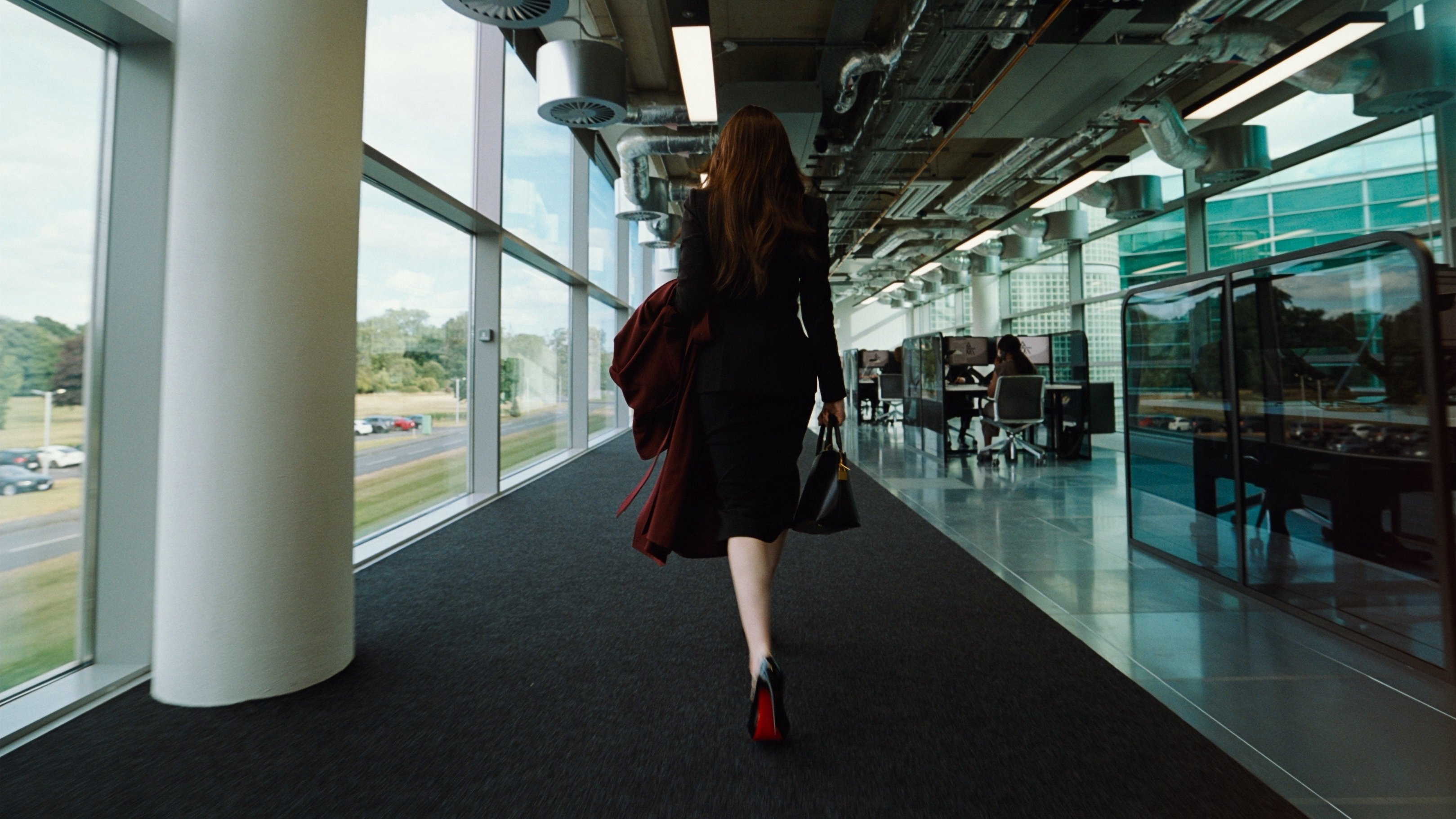 Caption: a woman in a black dress walking down a hallway