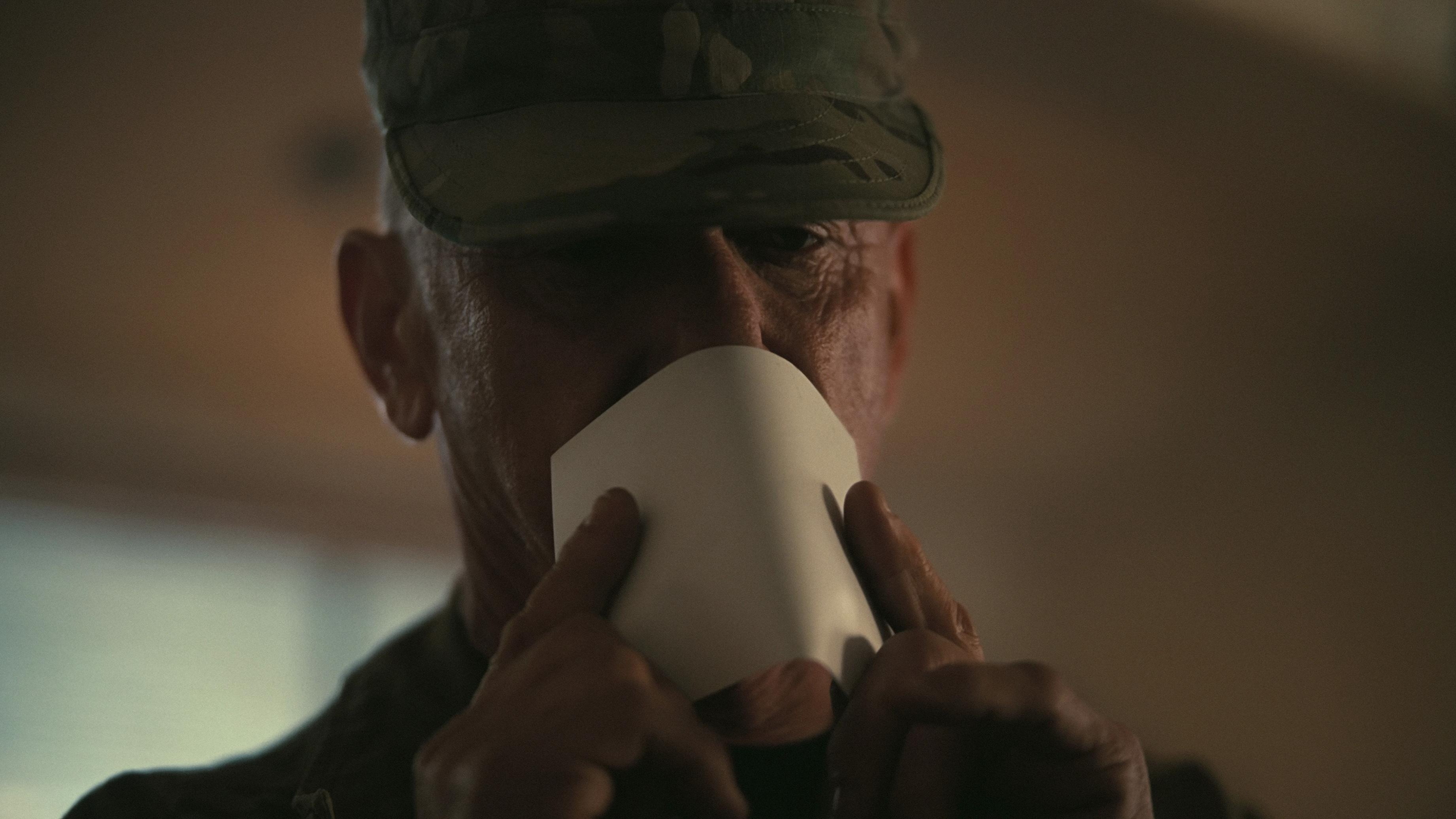 Caption: a man in a military uniform is drinking from a paper cup