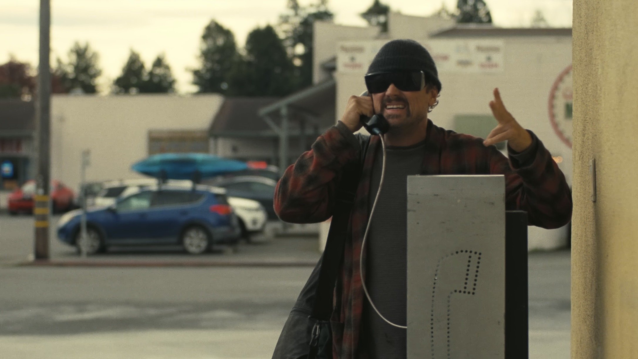 Caption: a man talking on a cell phone next to a sign