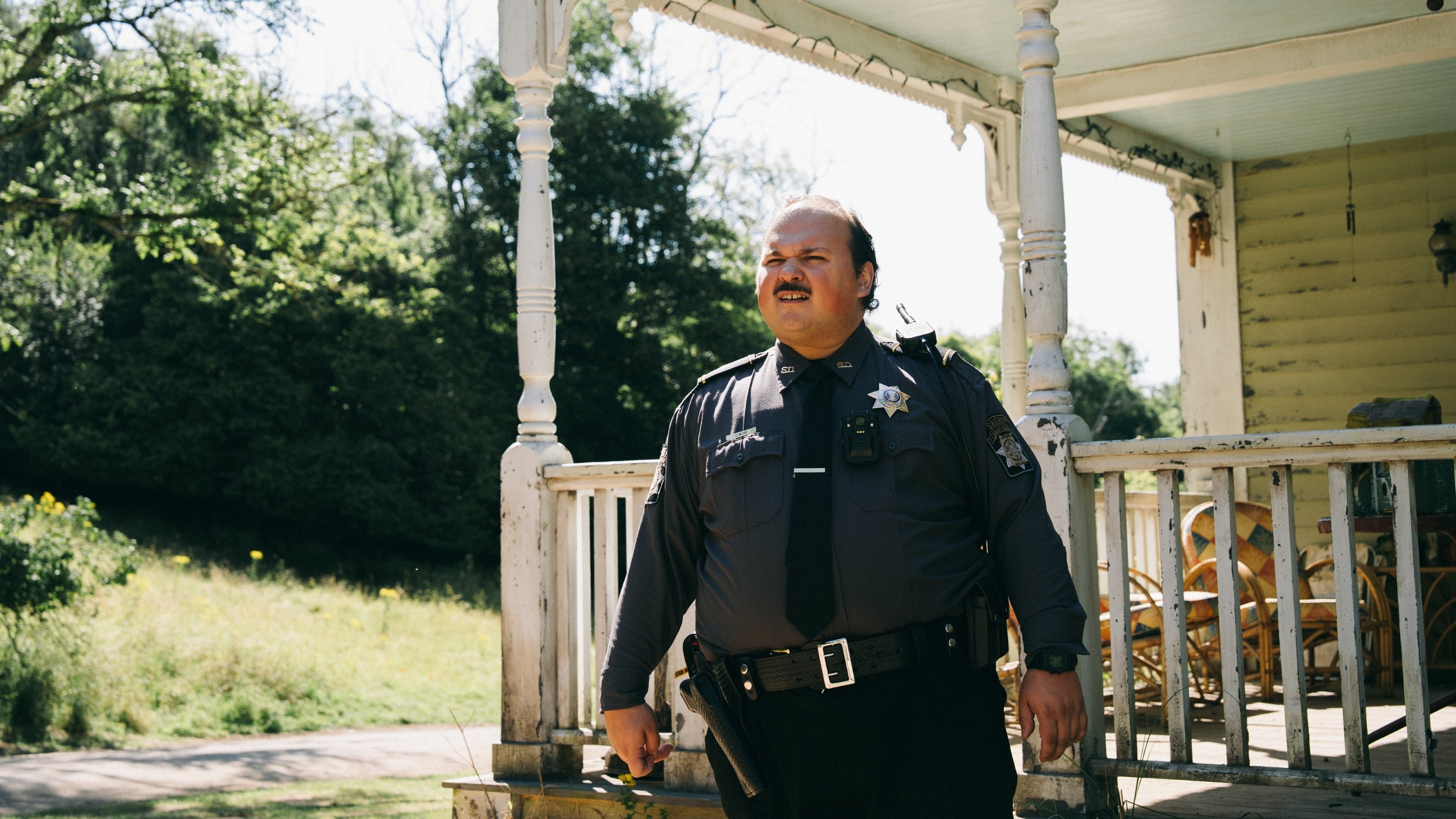 Caption: a police officer standing on the porch of a house