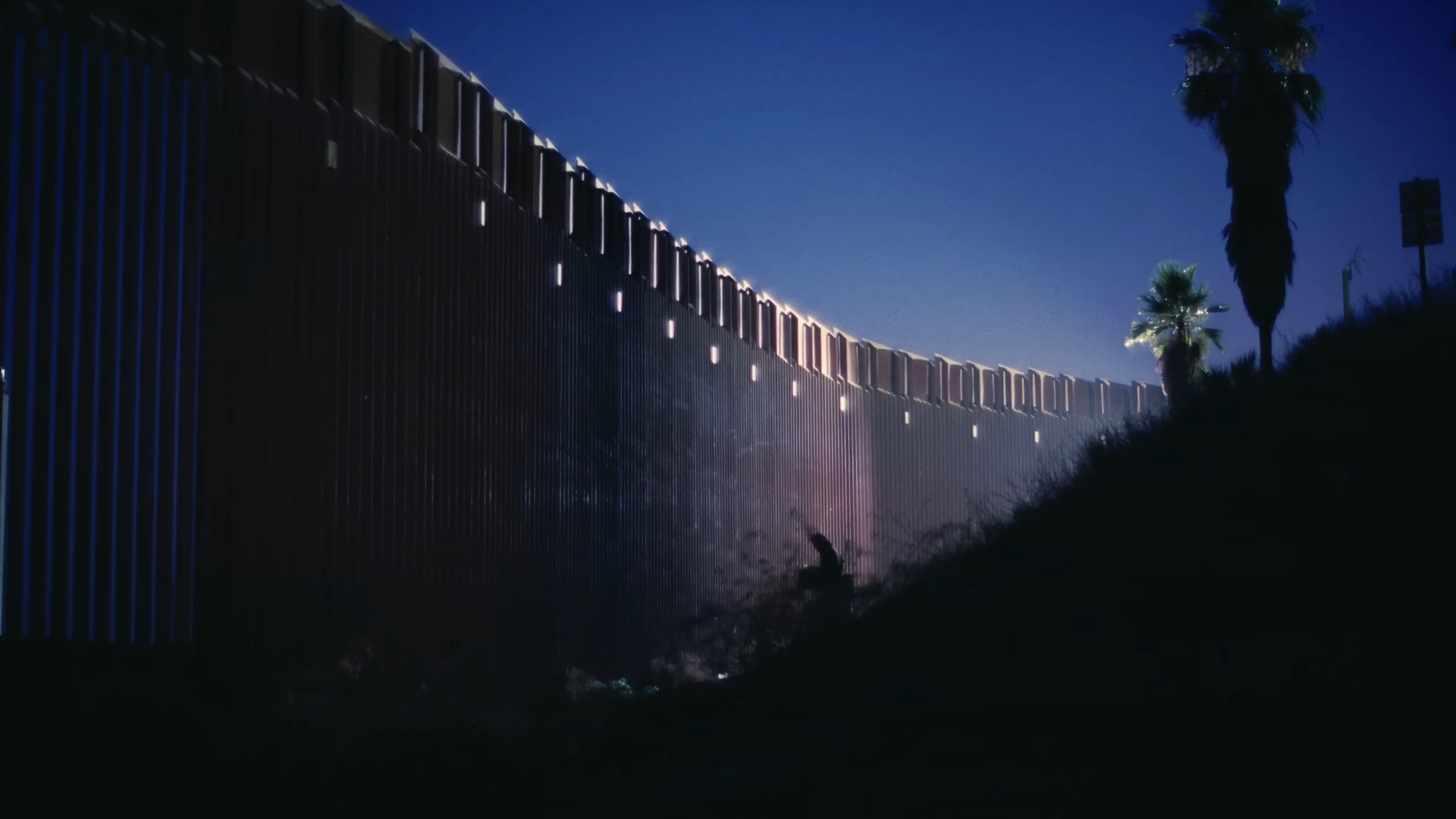 Caption: a person standing in front of a fence at night