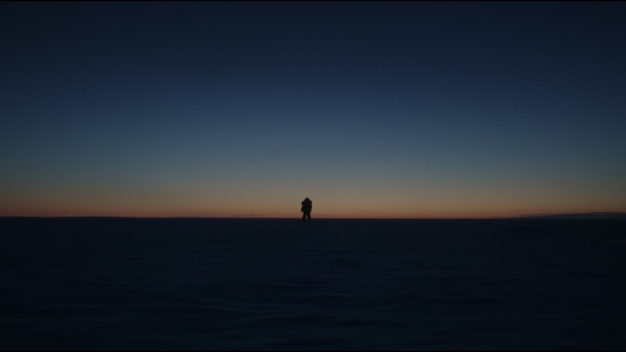 Caption: a lone person standing in the middle of the night