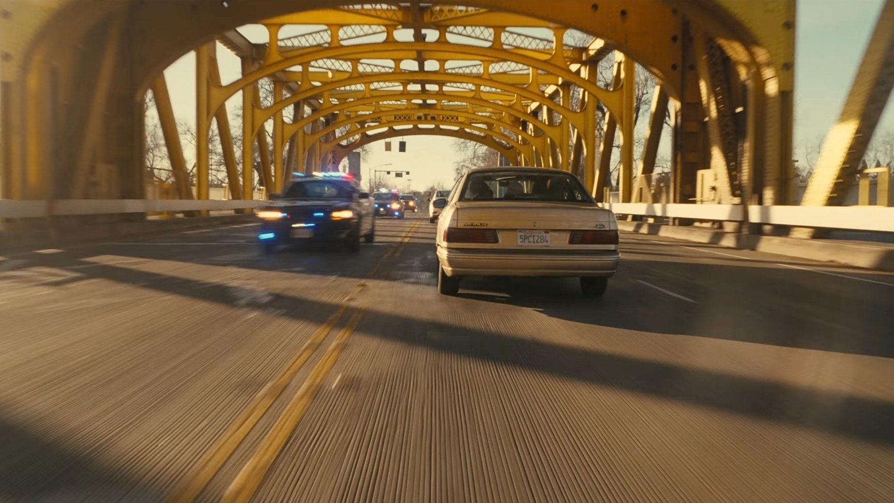 Caption: a police car and a police car driving on a bridge