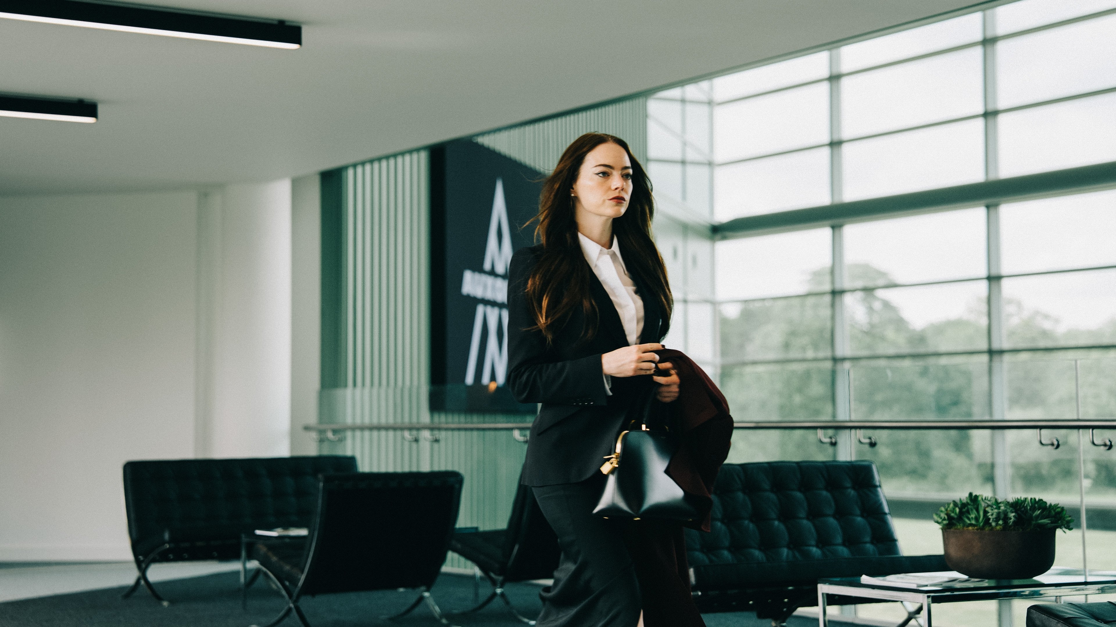 Caption: a woman in a suit walking through a lobby