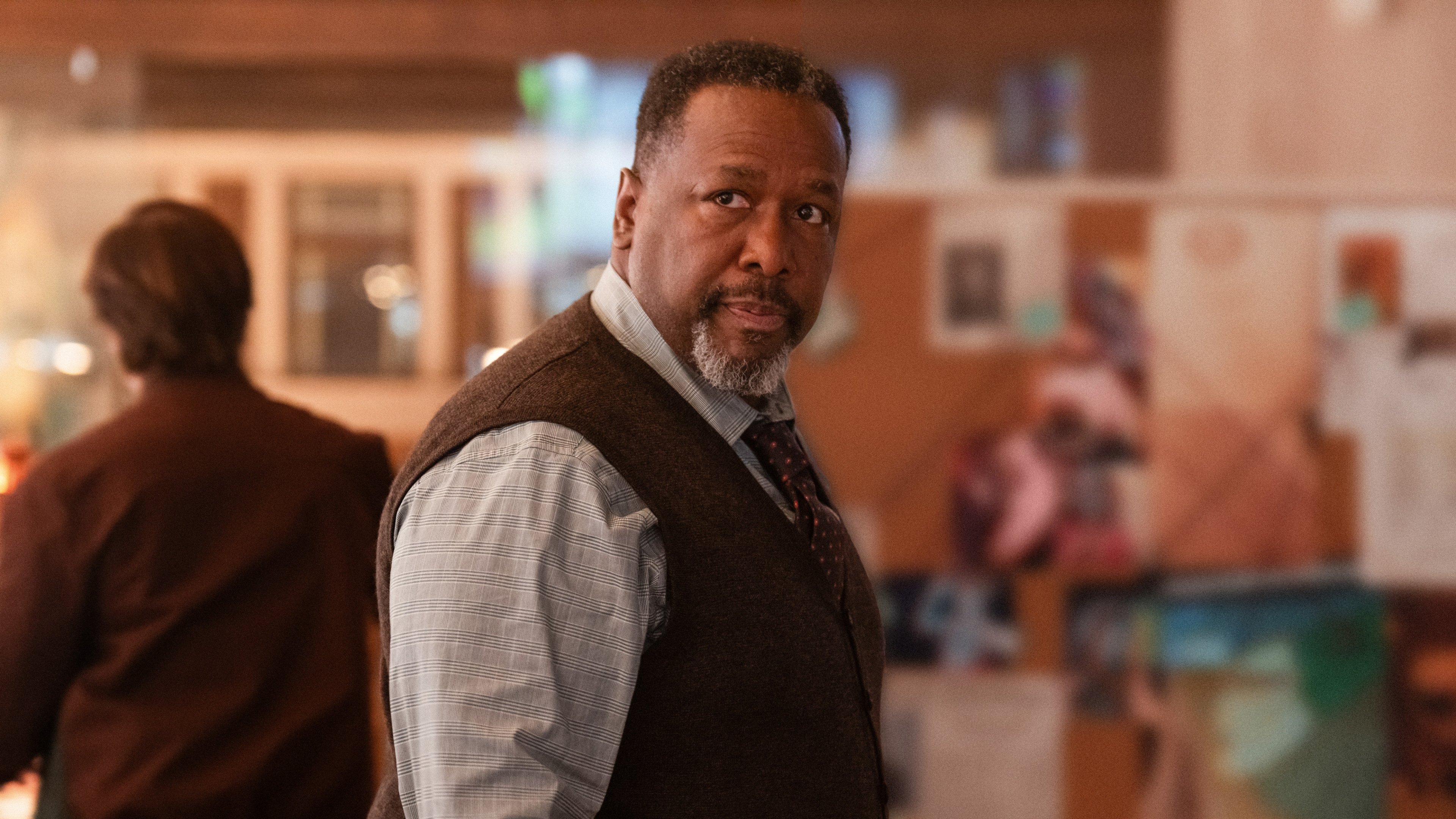 Caption: a man in a vest and tie standing in a room