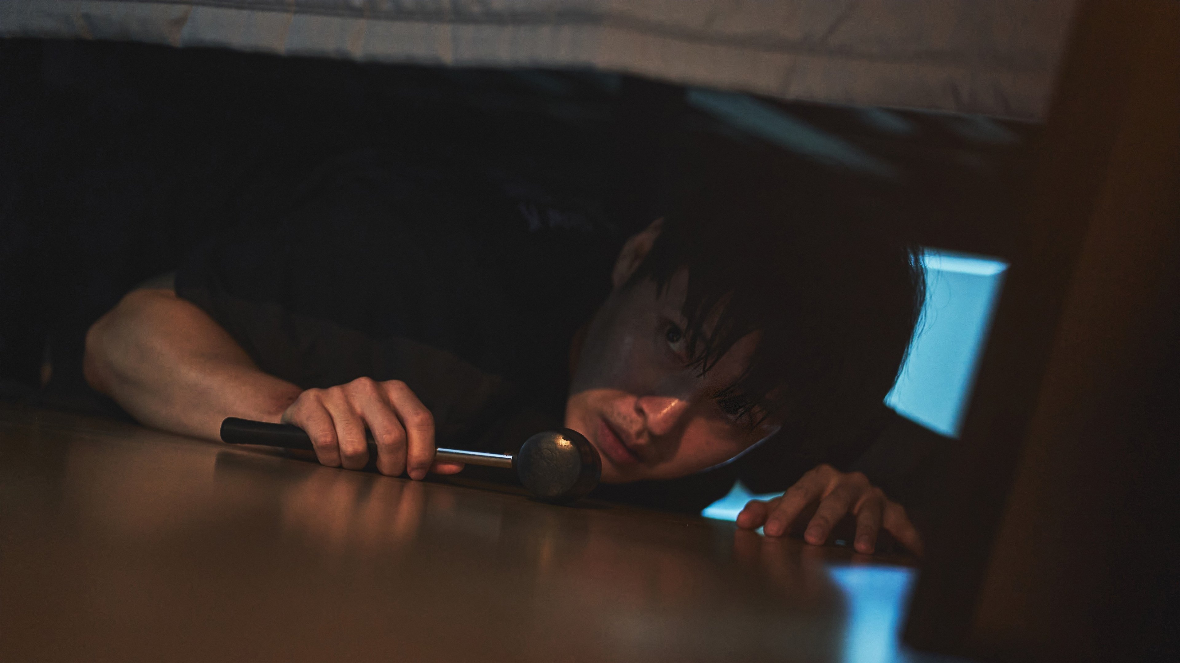 Caption: a young boy is hiding under a bed