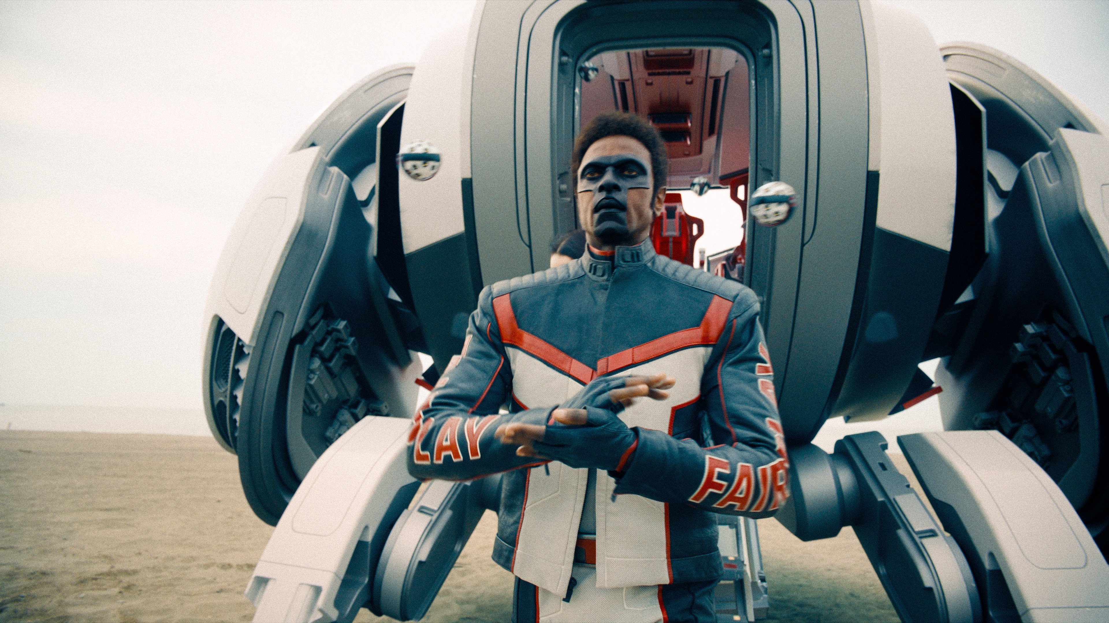 Caption: a man standing in front of a futuristic vehicle