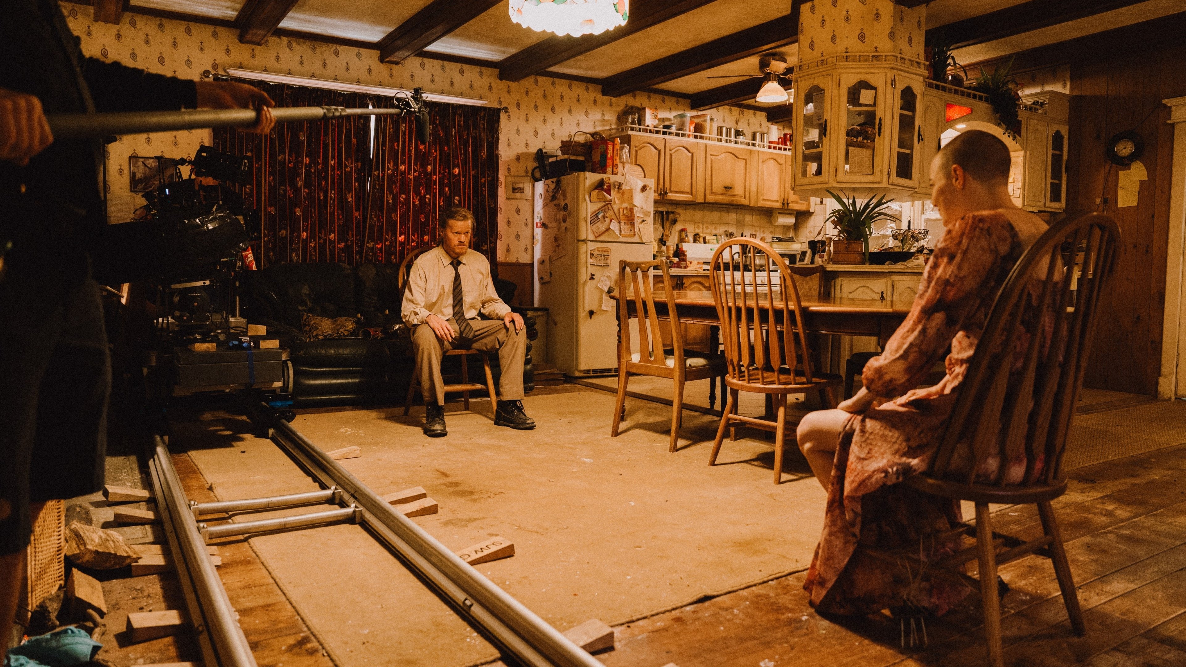 Caption: a man sitting in a chair next to a woman in a kitchen